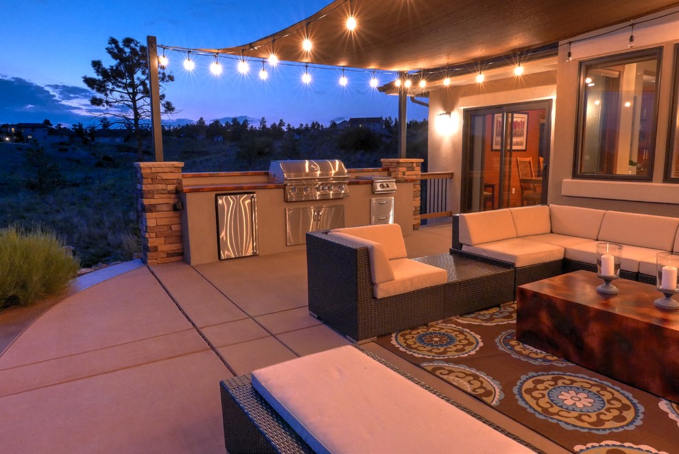This is an example of a large eclectic backyard patio in Denver with concrete pavers, an outdoor kitchen and an awning.