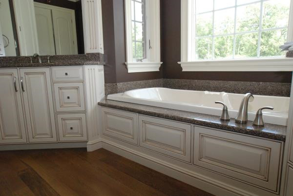 Inspiration for a mid-sized traditional master bathroom in Columbus with beaded inset cabinets, white cabinets, a corner tub, brown walls, medium hardwood floors, an undermount sink and granite benchtops.
