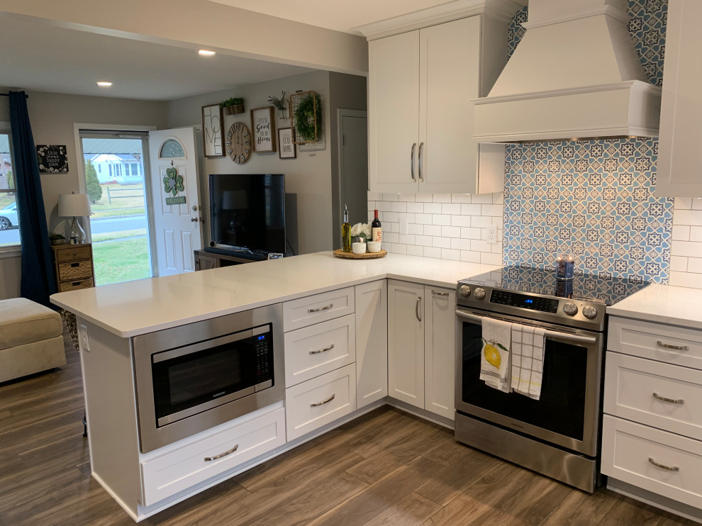 Inspiration for a mid-sized transitional u-shaped vinyl floor and brown floor open concept kitchen remodel with an undermount sink, shaker cabinets, white cabinets, quartz countertops, white backsplash, stainless steel appliances, a peninsula and white countertops