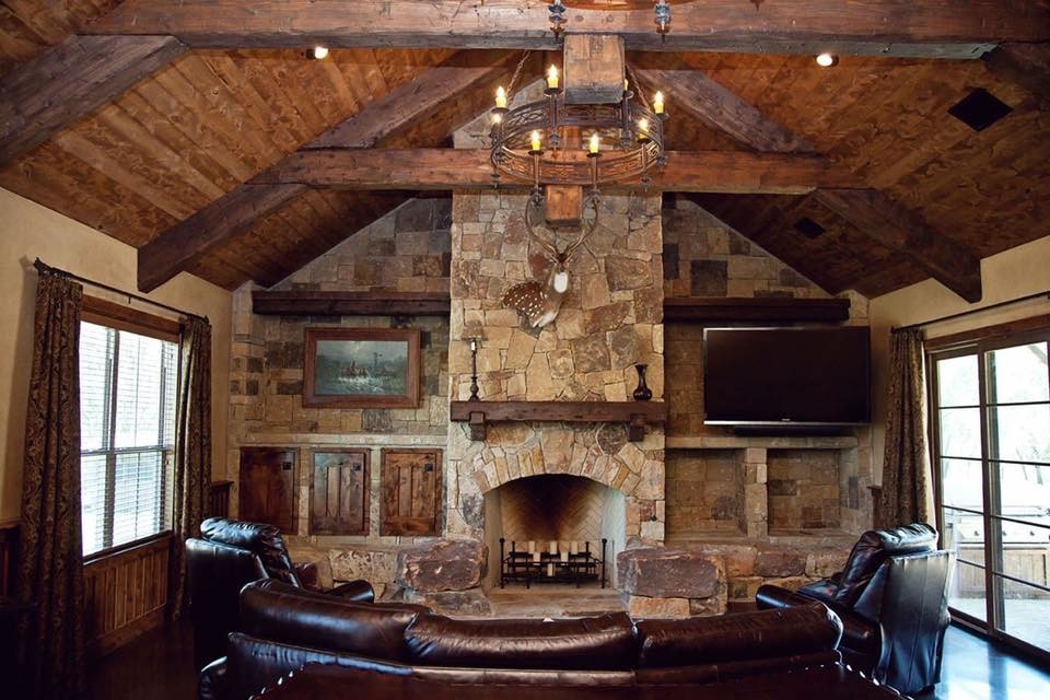 Design ideas for a mid-sized country enclosed family room in Austin with beige walls, concrete floors, a standard fireplace, a stone fireplace surround, a wall-mounted tv and brown floor.