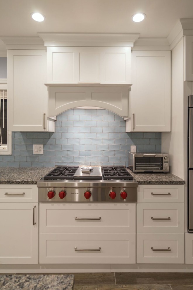 Eat-in kitchen - mid-sized transitional u-shaped porcelain tile eat-in kitchen idea in Orange County with an undermount sink, shaker cabinets, white cabinets, granite countertops, blue backsplash, glass tile backsplash, stainless steel appliances and an island