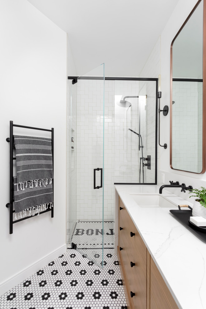 This is an example of a mid-sized scandinavian kids bathroom in Montreal with beaded inset cabinets, light wood cabinets, an alcove shower, a one-piece toilet, white tile, ceramic tile, white walls, mosaic tile floors, an undermount sink, engineered quartz benchtops, black floor, a hinged shower door, white benchtops, a niche, a double vanity and a built-in vanity.