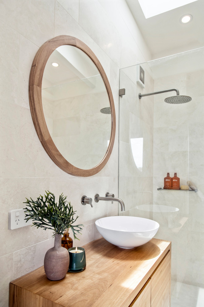 Modern inredning av ett litet badrum med dusch, med släta luckor, skåp i ljust trä, en öppen dusch, grå kakel, ett fristående handfat, träbänkskiva och med dusch som är öppen