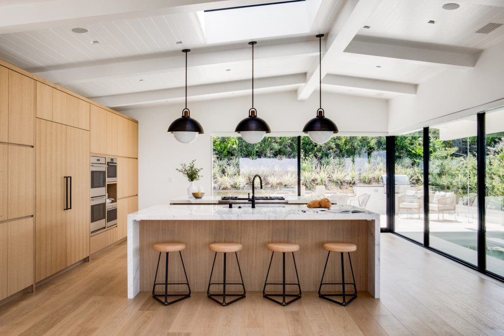 Mid-century modern light wood floor and beige floor kitchen photo in Orange County with marble countertops, two islands, white countertops, flat-panel cabinets, light wood cabinets and paneled appliances