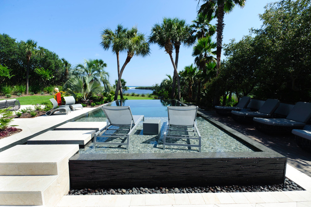 Photo of a contemporary infinity pool in Miami with concrete pavers.