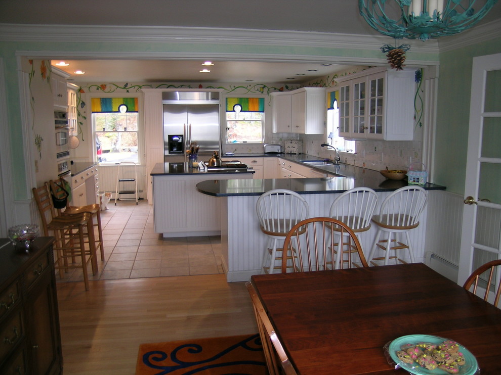 Inspiration for a large country u-shaped eat-in kitchen in Portland Maine with an undermount sink, louvered cabinets, white cabinets, white splashback, porcelain splashback, stainless steel appliances, ceramic floors, with island and granite benchtops.
