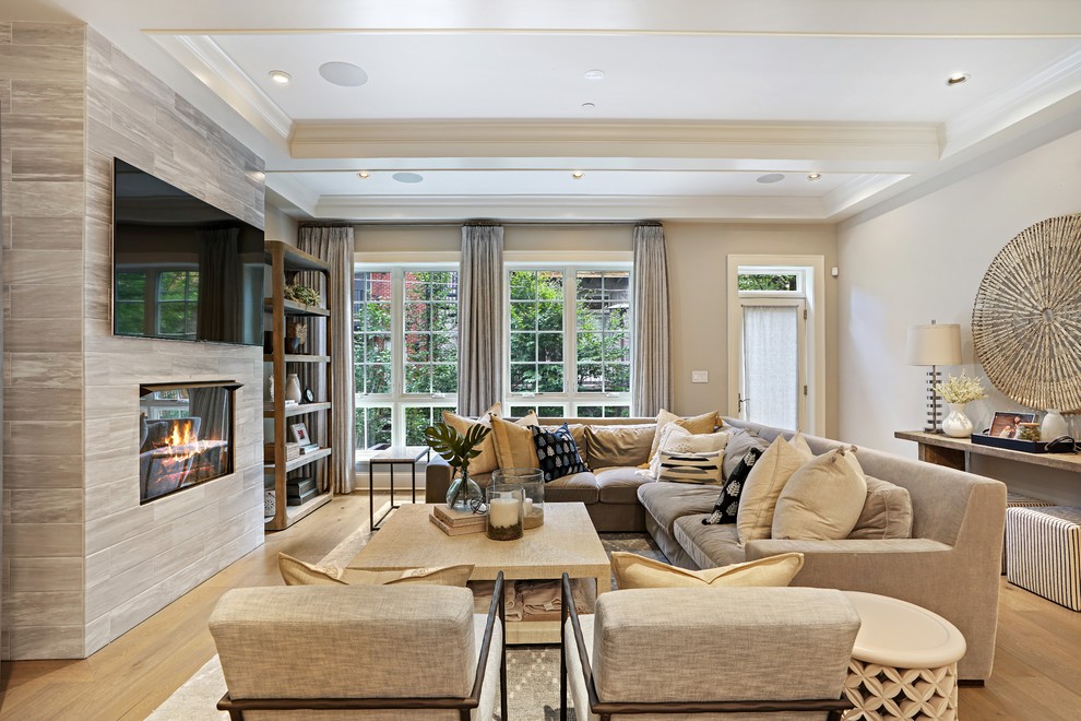 Design ideas for a transitional family room in Chicago with beige walls, medium hardwood floors, a standard fireplace, a tile fireplace surround, a wall-mounted tv and brown floor.