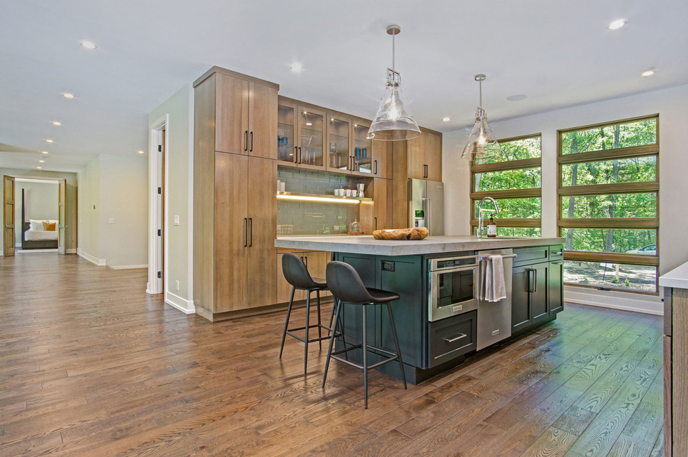 Kitchen - rustic medium tone wood floor kitchen idea in Grand Rapids with an undermount sink, flat-panel cabinets, quartz countertops, green backsplash, glass tile backsplash and stainless steel appliances