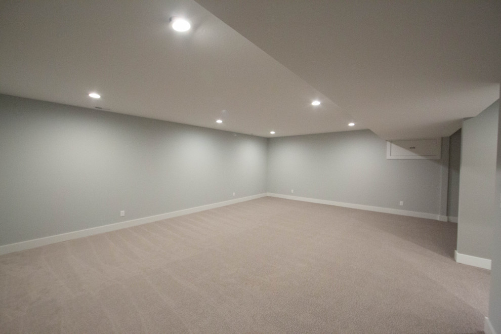 Medium sized classic fully buried basement in Indianapolis with grey walls, carpet and brown floors.