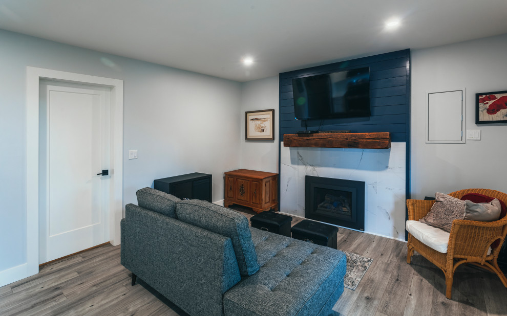 This is an example of an expansive country open concept living room in Vancouver with white walls, vinyl floors, a standard fireplace, a tile fireplace surround, a wall-mounted tv, brown floor and planked wall panelling.