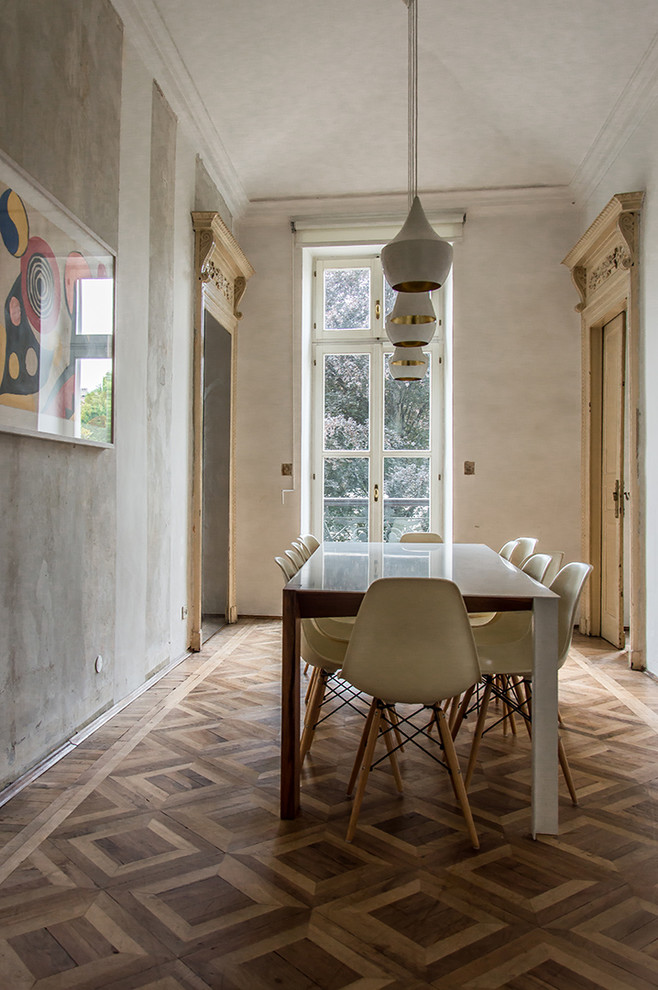 Photo of an industrial dining room in Turin with grey walls, medium hardwood floors and brown floor.