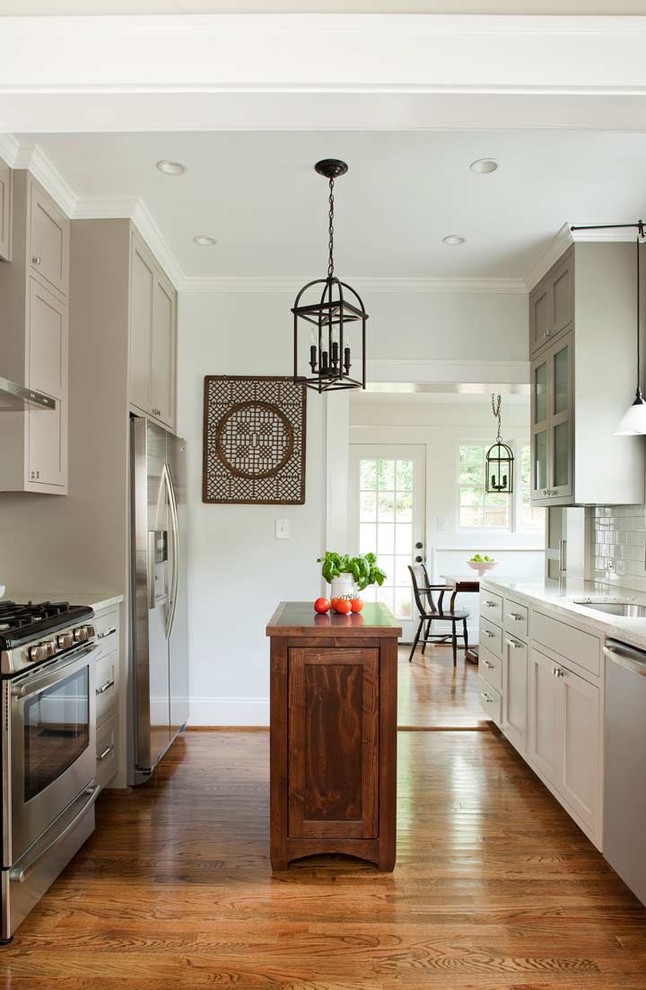 Design ideas for a transitional galley kitchen in Atlanta with an undermount sink, recessed-panel cabinets, grey cabinets, granite benchtops, white splashback, subway tile splashback and stainless steel appliances.