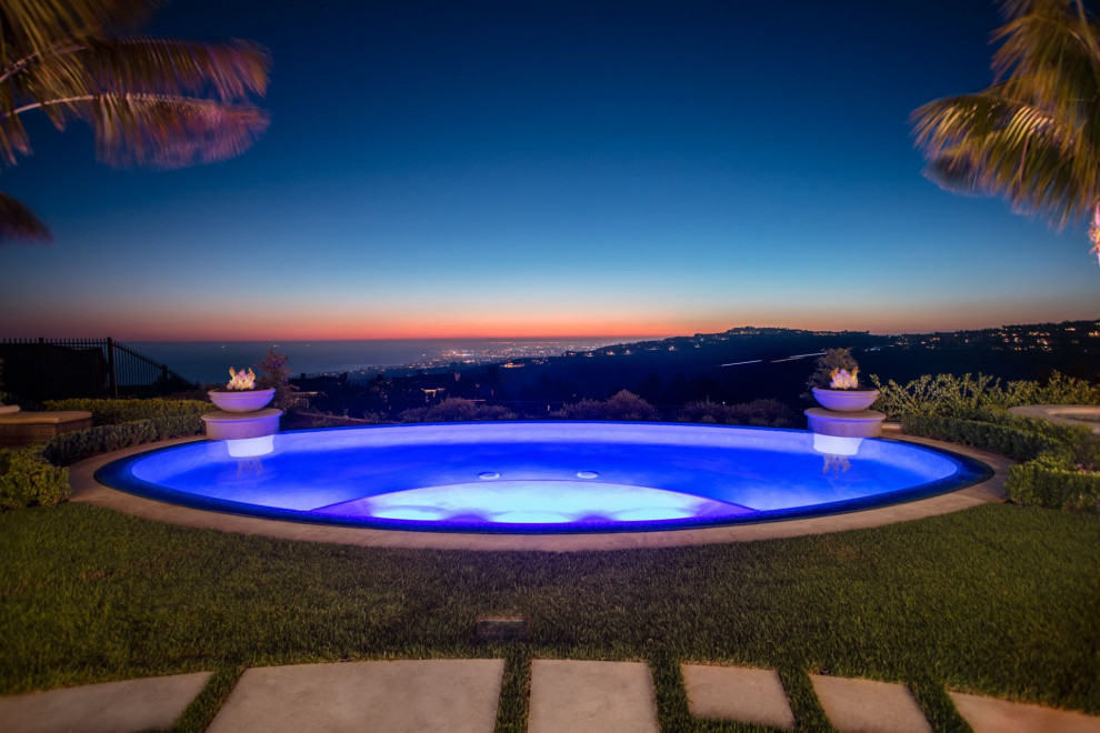 Inspiration for a mid-sized mediterranean backyard stamped concrete and custom-shaped infinity pool house remodel in Orange County