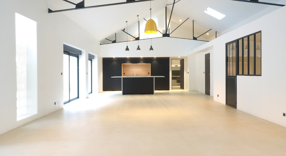 Aménagement d'un grand salon industriel fermé avec un mur blanc, aucune cheminée, aucun téléviseur et un sol beige.