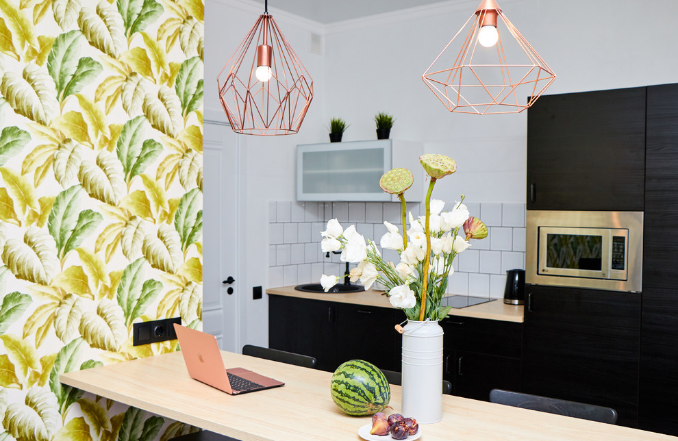 Photo of a small scandinavian galley eat-in kitchen in Other with a drop-in sink, flat-panel cabinets, black cabinets, wood benchtops, subway tile splashback, laminate floors, with island and black floor.