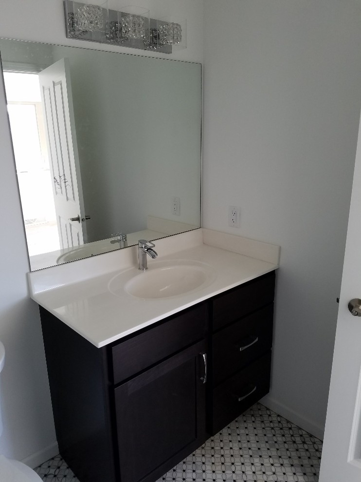 Mid-sized arts and crafts 3/4 marble floor and multicolored floor bathroom photo with flat-panel cabinets, black cabinets, an integrated sink and solid surface countertops