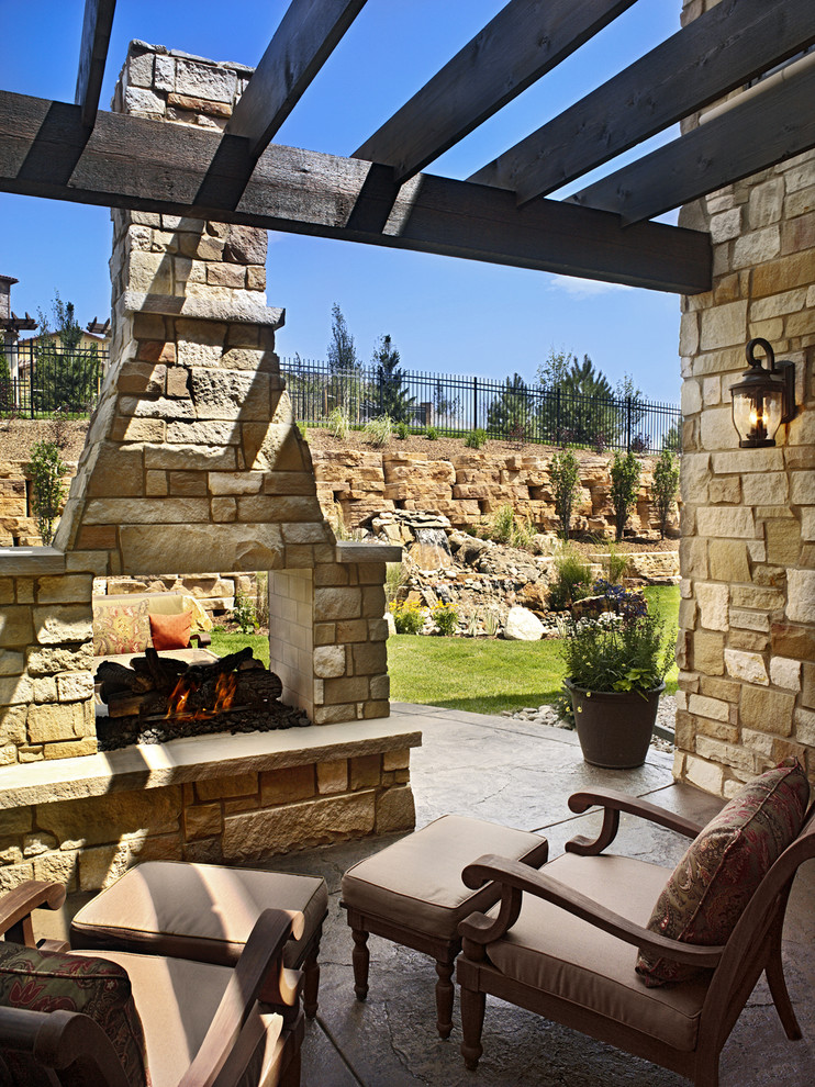 Photo of a mid-sized traditional backyard patio in Denver with a fire feature, stamped concrete and a pergola.
