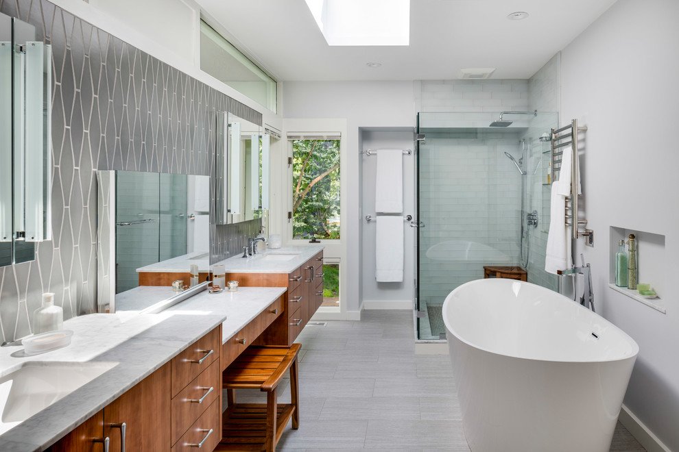 Midcentury master bathroom in Boston with flat-panel cabinets, medium wood cabinets, a freestanding tub, a corner shower, gray tile, grey walls, an undermount sink, grey floor, a hinged shower door and grey benchtops.