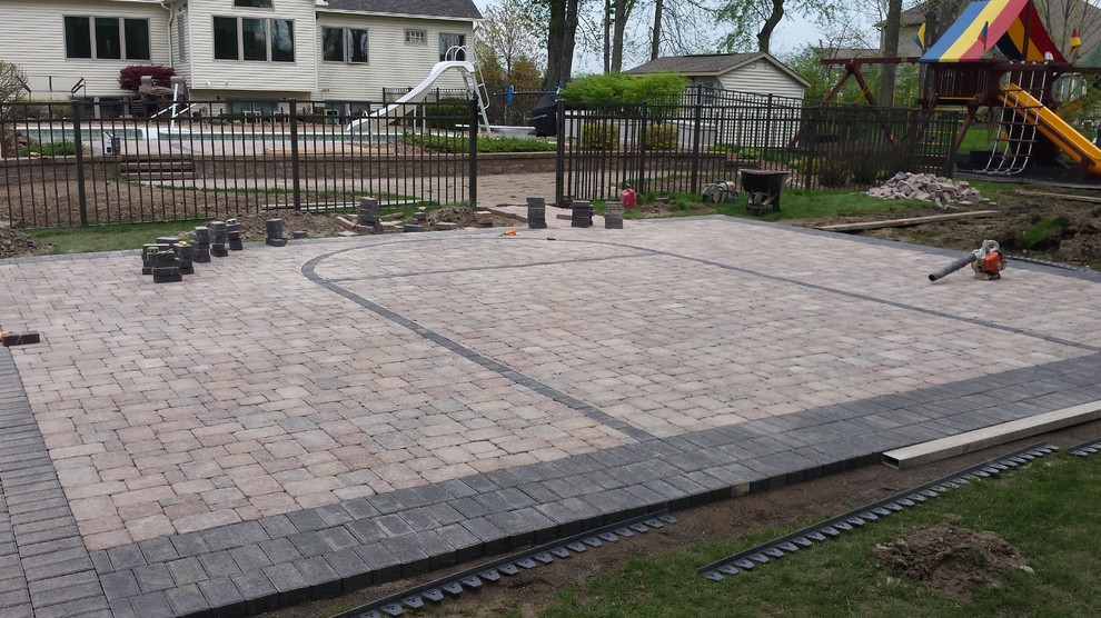 This is an example of a large modern backyard patio in New York with brick pavers.