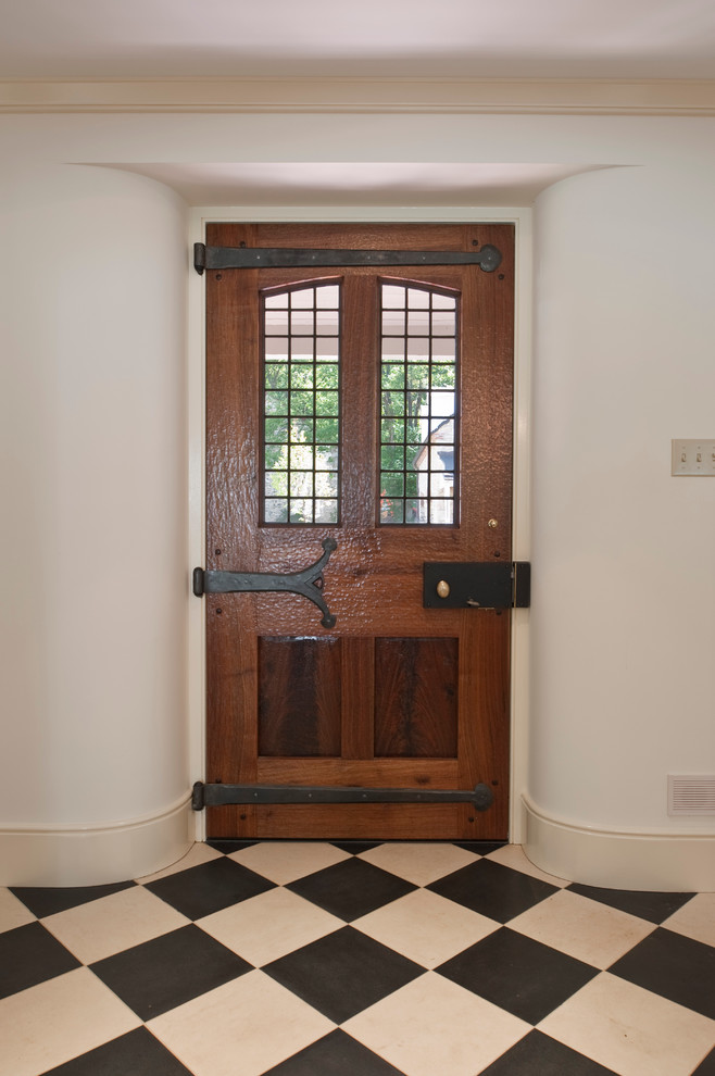 This is an example of a country front door in Philadelphia with white walls, a single front door, a dark wood front door and marble floors.