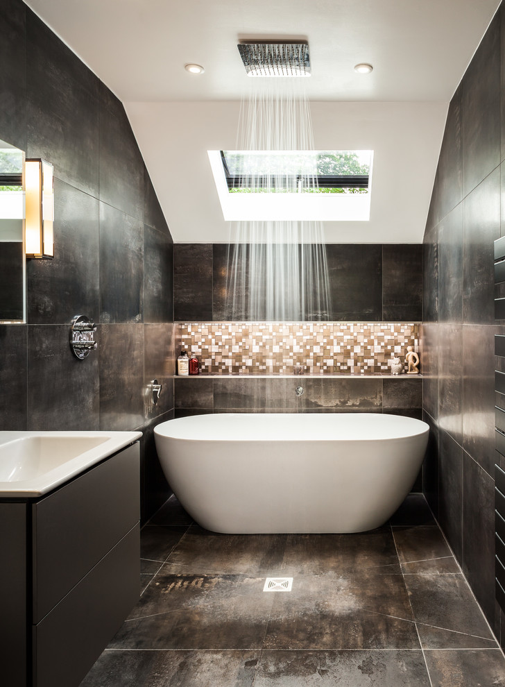 Photo of a mid-sized contemporary wet room bathroom in Surrey with flat-panel cabinets, grey cabinets, a freestanding tub, black walls, brown floor, an open shower, black tile, brown tile, mosaic tile and a console sink.