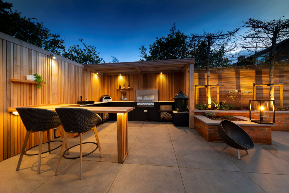 Photo of a mid-sized contemporary backyard patio in Surrey with natural stone pavers and a pergola.