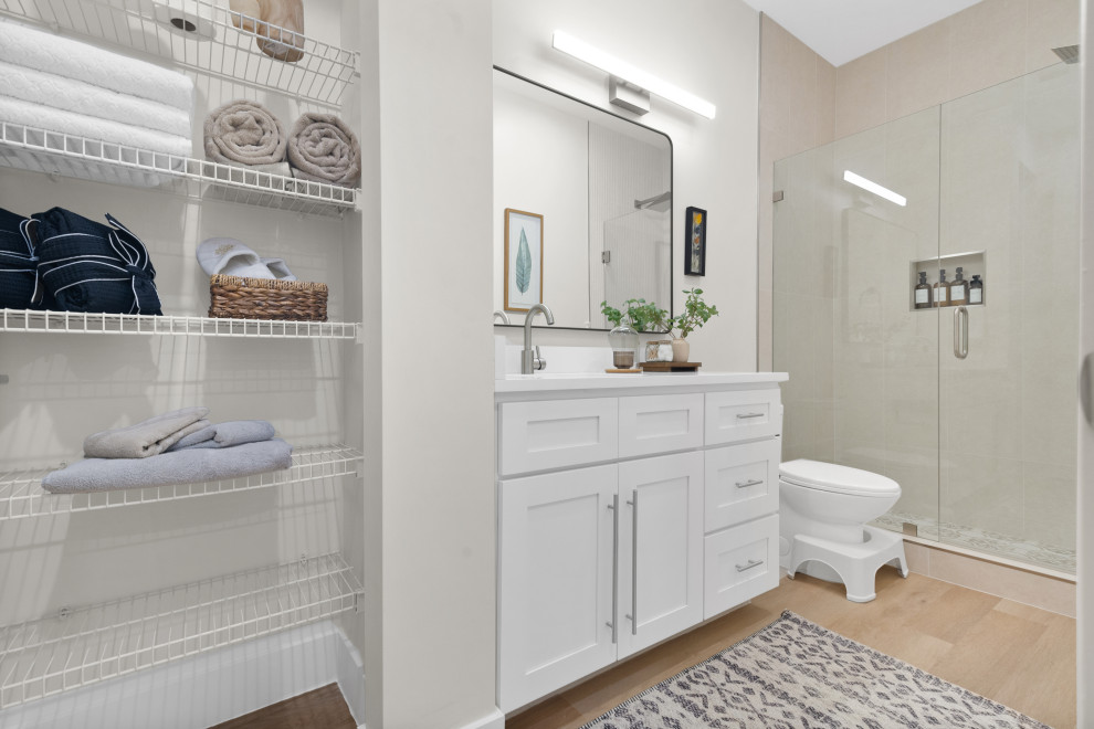 Mid-sized scandinavian master bathroom in Miami with beaded inset cabinets, white cabinets, an alcove shower, a one-piece toilet, beige tile, ceramic tile, white walls, vinyl floors, a drop-in sink, limestone benchtops, beige floor, a hinged shower door, white benchtops, an enclosed toilet, a single vanity, a floating vanity and vaulted.