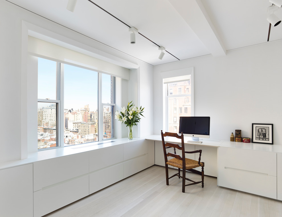 Inspiration for a mid-sized contemporary study room in New York with white walls, light hardwood floors, a built-in desk, no fireplace and beige floor.