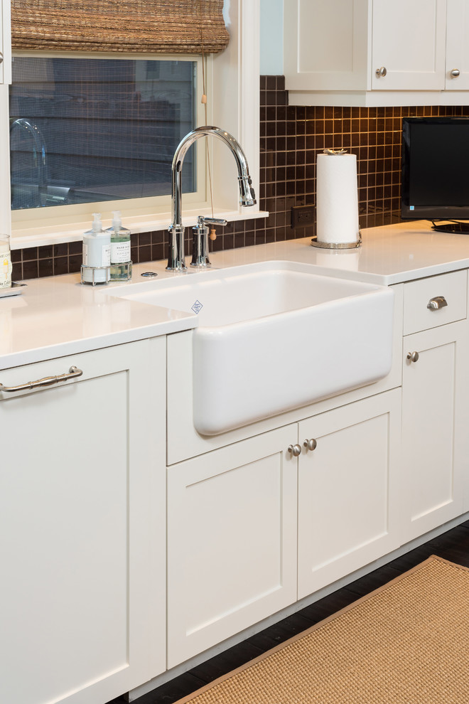 Inspiration for a mid-sized transitional l-shaped dark wood floor and brown floor enclosed kitchen remodel with a farmhouse sink, shaker cabinets, white cabinets, quartzite countertops, brown backsplash, mosaic tile backsplash, stainless steel appliances, an island and white countertops
