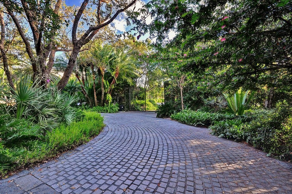 Design ideas for a tropical driveway in Miami with natural stone pavers.