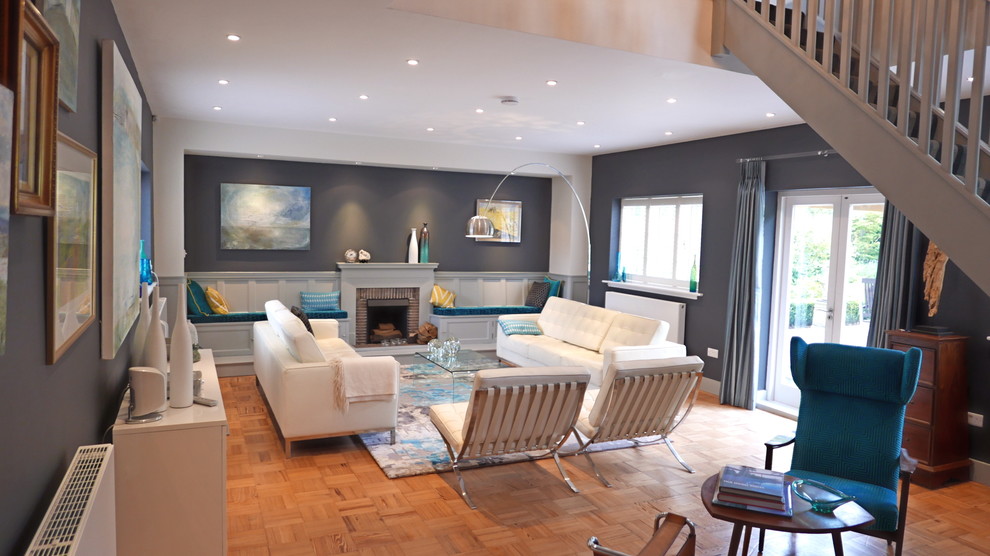 Mid-sized contemporary enclosed living room in Surrey with blue walls, light hardwood floors, a standard fireplace, a brick fireplace surround and orange floor.