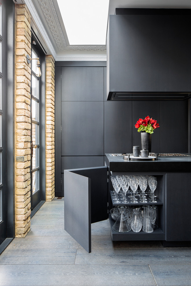 Large eclectic single-wall open plan kitchen in London with flat-panel cabinets, black cabinets, concrete benchtops, dark hardwood floors, with island and brown floor.