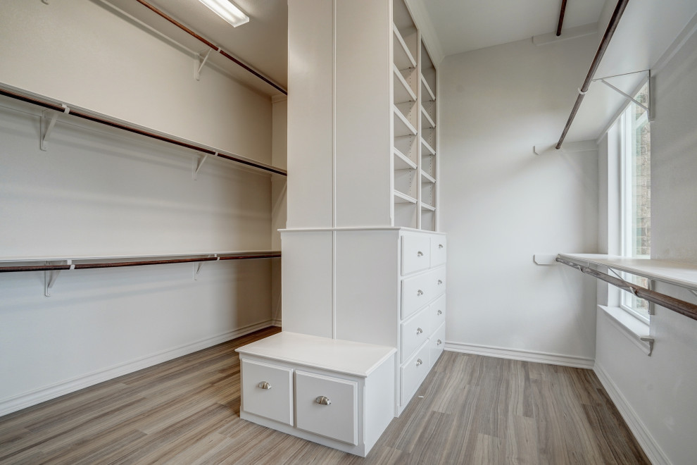 This is an example of a large traditional gender-neutral walk-in wardrobe with flat-panel cabinets, grey cabinets, vinyl floors and brown floor.