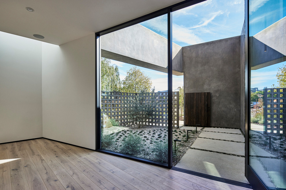 Geräumiger Moderner Eingang mit Vestibül, beiger Wandfarbe, Betonboden, Drehtür, schwarzer Haustür, grauem Boden und Holzwänden in Los Angeles