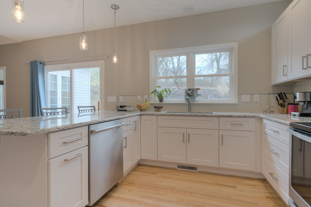 Eat-in kitchen - mid-sized transitional u-shaped light wood floor eat-in kitchen idea with an undermount sink, shaker cabinets, white cabinets, quartz countertops, beige backsplash, glass tile backsplash, stainless steel appliances and a peninsula