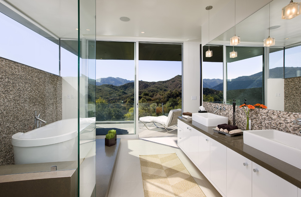 This is an example of a large contemporary master bathroom in Los Angeles with flat-panel cabinets, white cabinets, a freestanding tub, a shower/bathtub combo, beige tile, mosaic tile, white walls, a drop-in sink and engineered quartz benchtops.