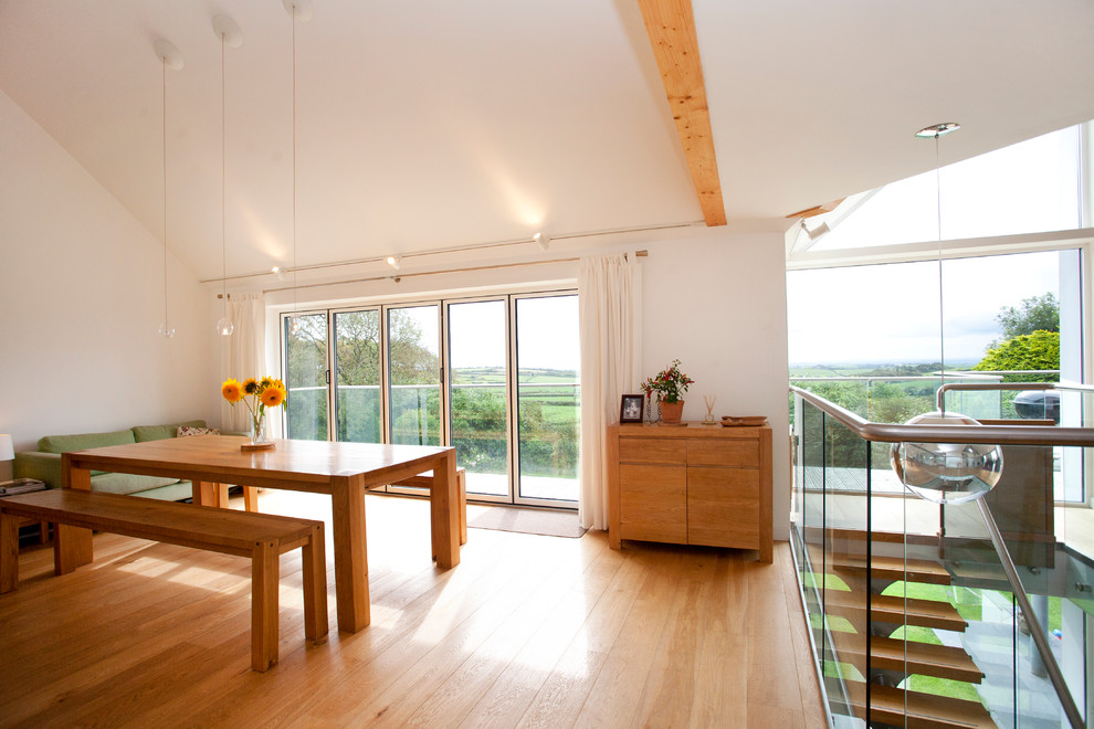 Contemporary dining room in Cornwall with white walls, medium hardwood floors and vaulted.