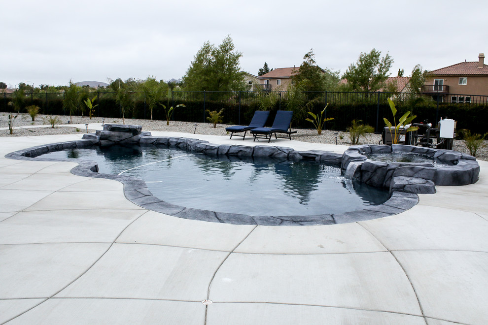 This is an example of a large tropical backyard custom-shaped pool in Los Angeles with concrete slab.