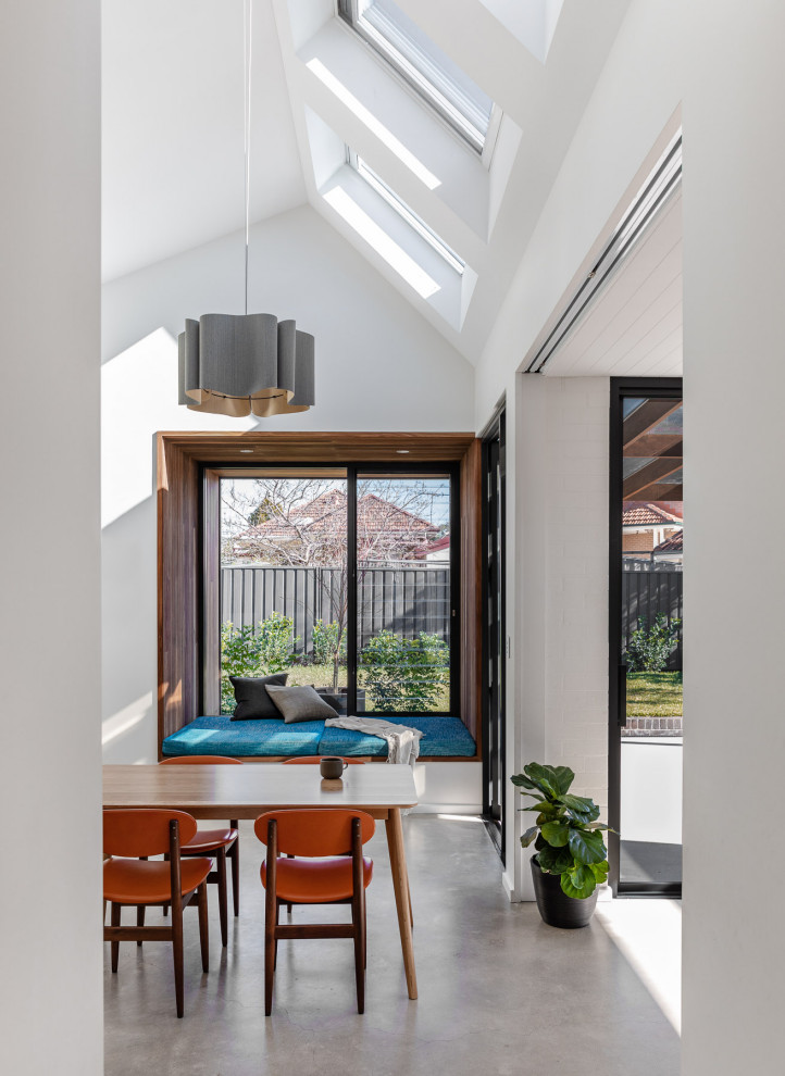 This is an example of a mid-sized modern kitchen/dining combo in Sydney with white walls, concrete floors, no fireplace, grey floor and vaulted.