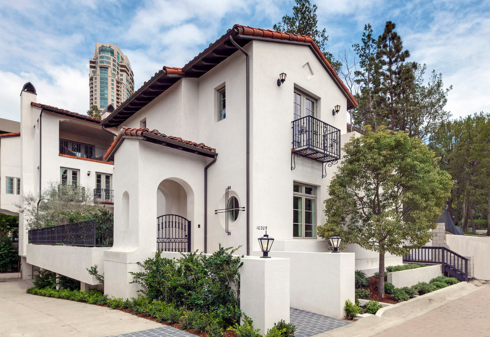 This is an example of a mediterranean two-storey white house exterior in Los Angeles with a gable roof and a tile roof.