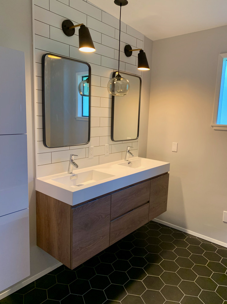 This is an example of a mid-sized midcentury bathroom in Seattle with medium wood cabinets, white tile, engineered quartz benchtops, black floor, white benchtops, flat-panel cabinets, an alcove tub, an alcove shower, a two-piece toilet, subway tile, grey walls, porcelain floors and a shower curtain.