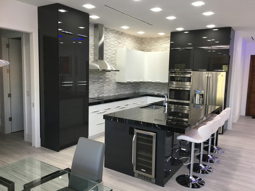 This is an example of a mid-sized modern l-shaped eat-in kitchen in Miami with an undermount sink, flat-panel cabinets, black cabinets, multi-coloured splashback, stainless steel appliances, plywood floors, with island, beige floor and black benchtop.