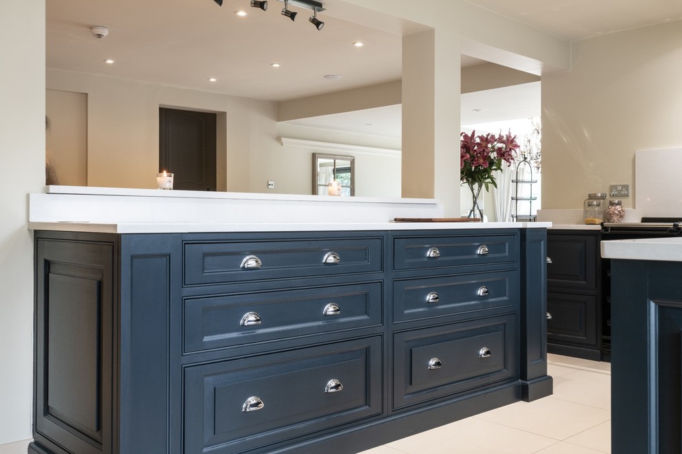 Photo of a large traditional l-shaped open plan kitchen in Essex with a double-bowl sink, raised-panel cabinets, blue cabinets, quartzite benchtops, ceramic floors, with island, beige floor and white benchtop.