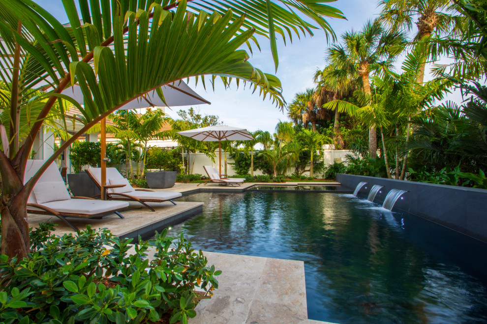 Immagine di una grande piscina naturale stile marinaro personalizzata in cortile con una vasca idromassaggio e pavimentazioni in pietra naturale