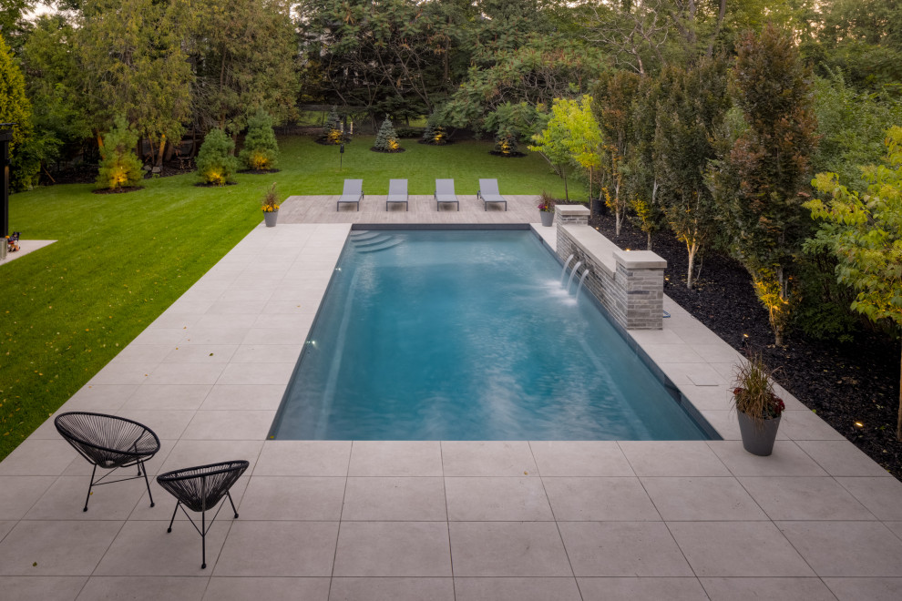 Modern back rectangular swimming pool in Toronto with tiled flooring.
