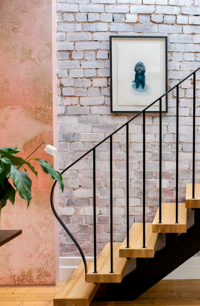 Wood straight staircase in Melbourne with open risers, metal railing and brick walls.