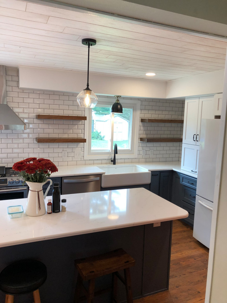 Large transitional l-shaped eat-in kitchen in Other with a farmhouse sink, shaker cabinets, blue cabinets, white splashback, subway tile splashback, laminate floors, with island, brown floor, white benchtop and wood.