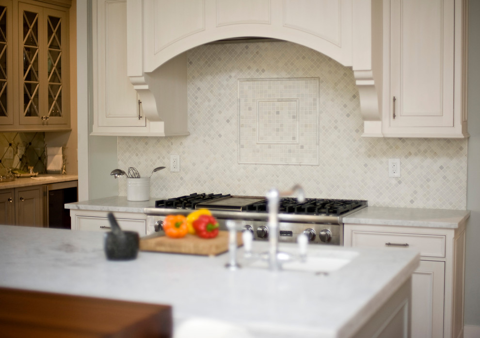 Transitional kitchen photo with recessed-panel cabinets, white cabinets, marble countertops, white backsplash, mosaic tile backsplash, stainless steel appliances, an island and an undermount sink