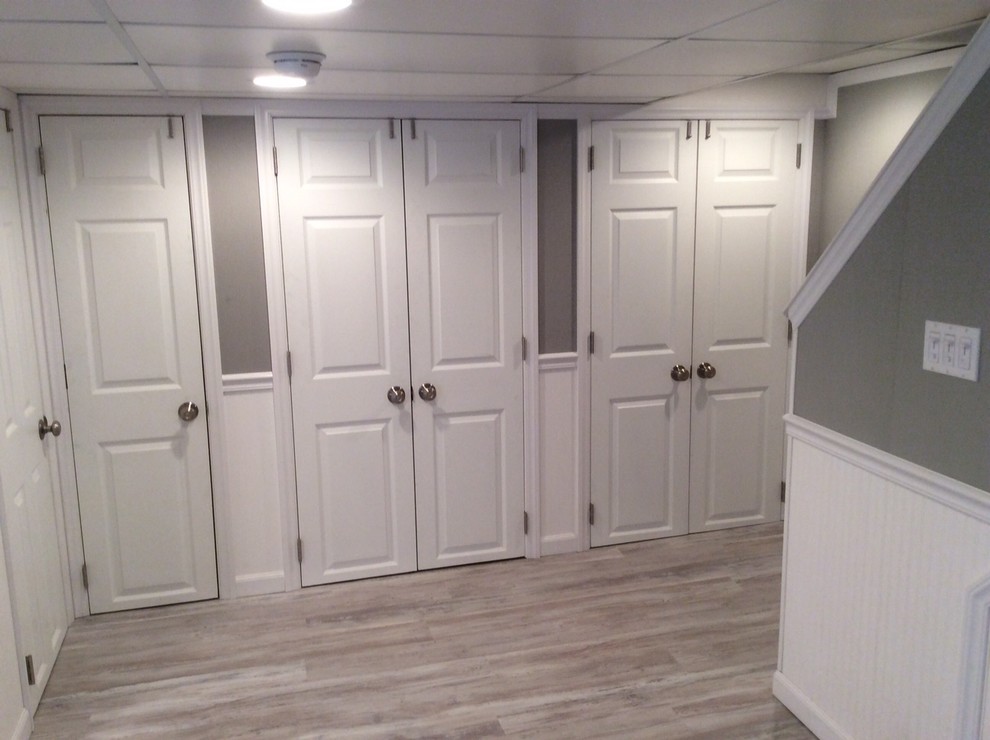Photo of a mid-sized transitional fully buried basement in New York with grey walls, light hardwood floors and no fireplace.