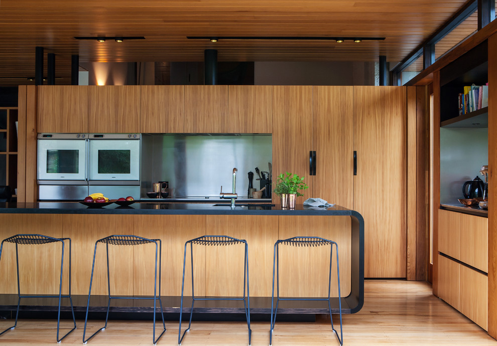 This is an example of a kitchen in Auckland with light hardwood floors.